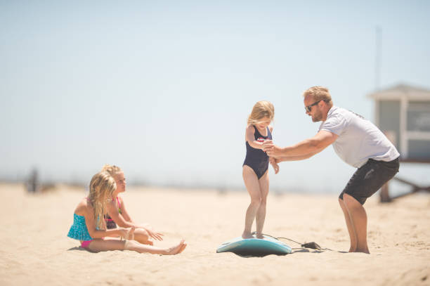 istock Athletic dad shows his daughters how to surf 811048462