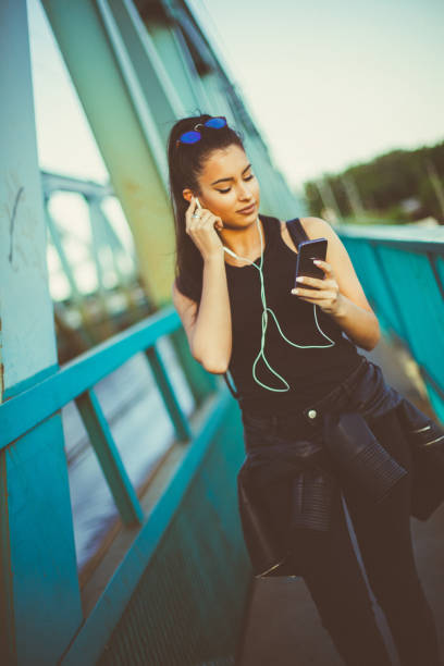 hermosa chica caminando y escuchando música en el puente - grand river audio fotografías e imágenes de stock