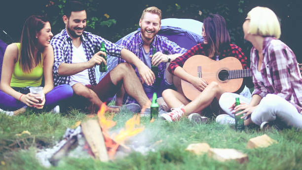 istock Five friends sitting next to campfire and singing song 811056194