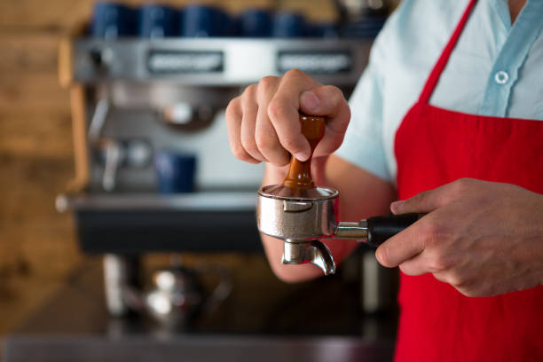 istock Barista using tamper to press ground coffee into portafilter in cafe 811089044