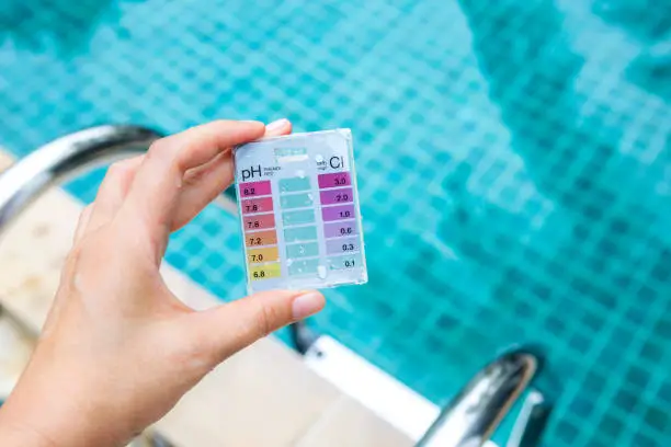 Photo of Girl hand holding mini water testing test kit over blurred swimming pool background