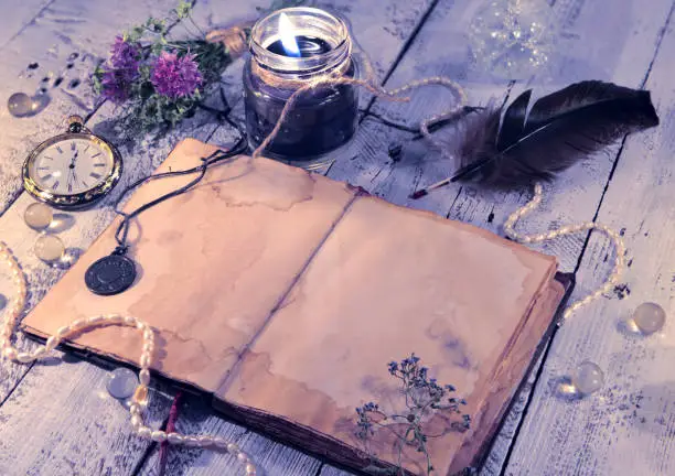 Photo of Open diary with clock, black candle, quill and medallion