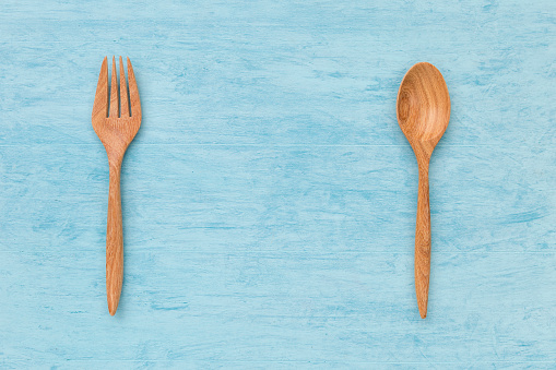 Natural wood texture of fork and spoon with space on blue texture background