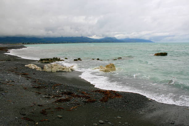 idyllische bucht von kaikoura wasser strand küste landschaft dramatischer himmel gewitterwolken, region canterbury, south neuseeland panorama - marlborough region zealand new landscape stock-fotos und bilder