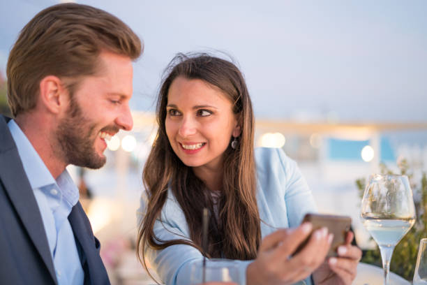 istock smiling couple with smart phone outside at dinner table 811156672
