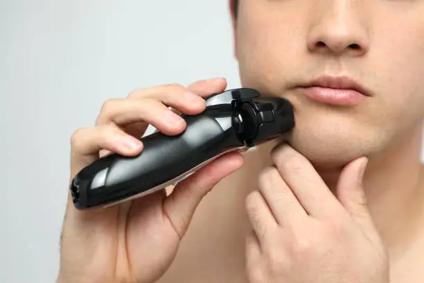 young man shaving his beard by electric shaver, men's beauty image