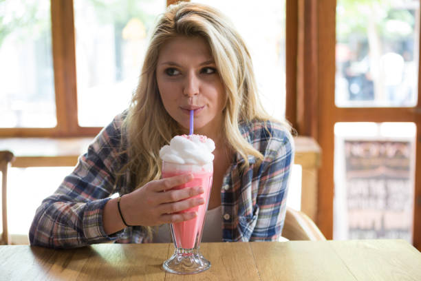istock Woman having milkshake at table in coffee shop 811168100