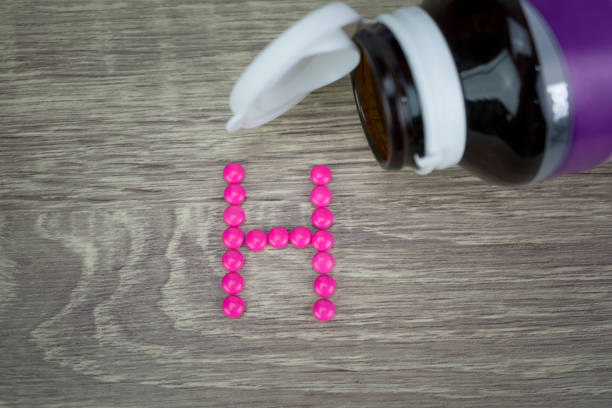 istock Pink pills forming shape to H alphabet on wood background 811214832