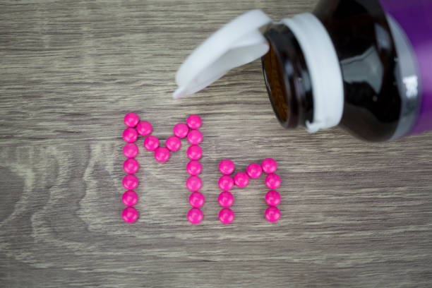 istock Pink pills forming shape to Mn alphabet on wood background 811215044