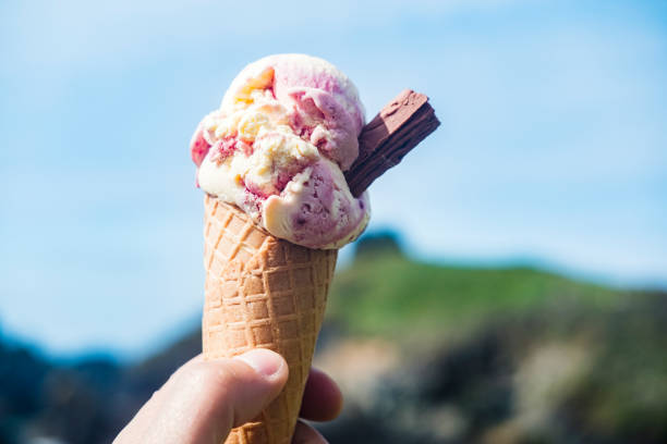 istock Hand holding strawberry ice-cream cone, South Cornwall Coast. 811219962