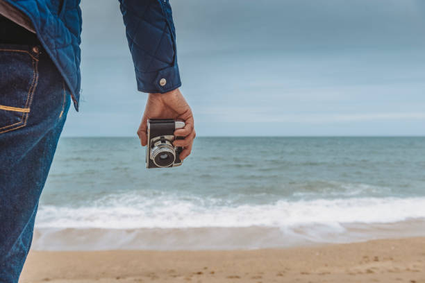 istock Hand holding old film camera by the beach, Porthleven, Cornwall 811219984