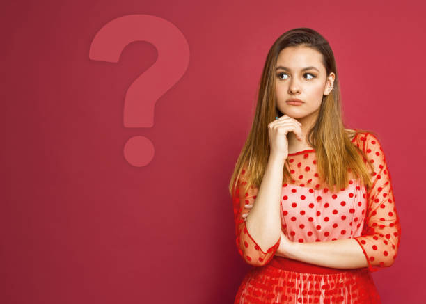 Woman looking up at question marks on a blackboard with copy space