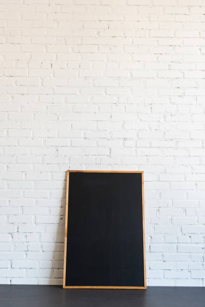 istock empty blackboard in wooden frame standing at white brick wall 811220418