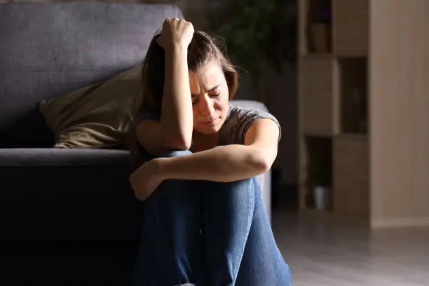 Photo of Sad teen at home in a dark living room