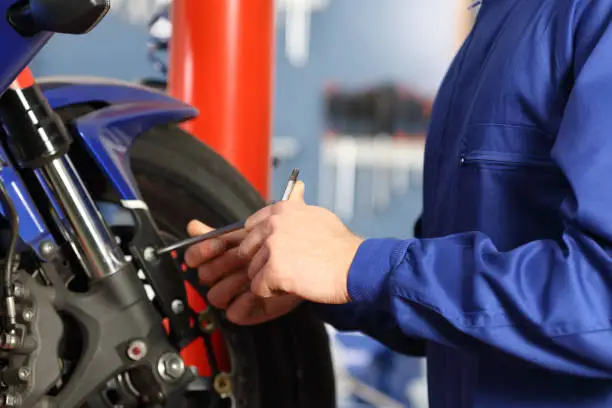 Motorbike mechanic hands disassembling parts in a workshop with equipment in the background