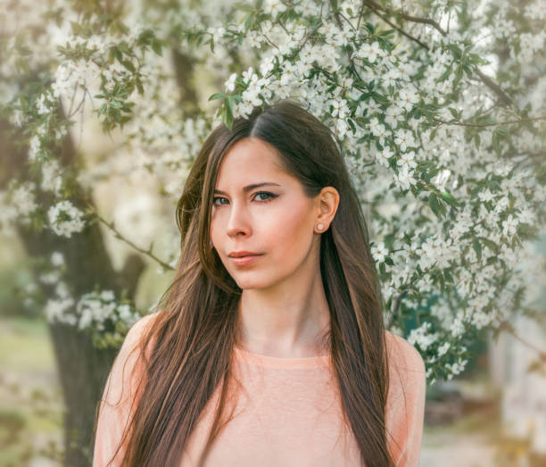 Beautiful young brunette girl in a blooming cherry orchard. Happy smiling young woman with spring flowers at garden. Girl in in spring garden among the blossoming cherry branches covered with flowers. 2632 stock pictures, royalty-free photos & images