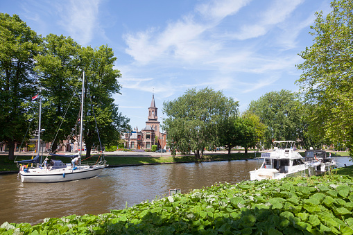 boats in canal near centre of old dutch town leeuwarden, capital of friesland, with church in the background
