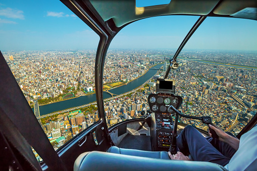 Helicopter cockpit inside the cabin flying on Tokyo city skyline, Sumida River Bridges and Asakusa area. Daytime. Tokyo, Japan.