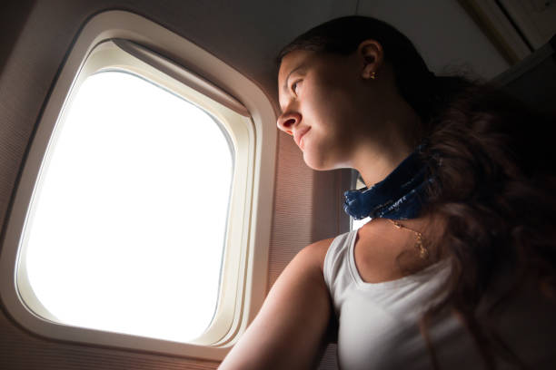 istock Young woman looking through window in airplane 811265954