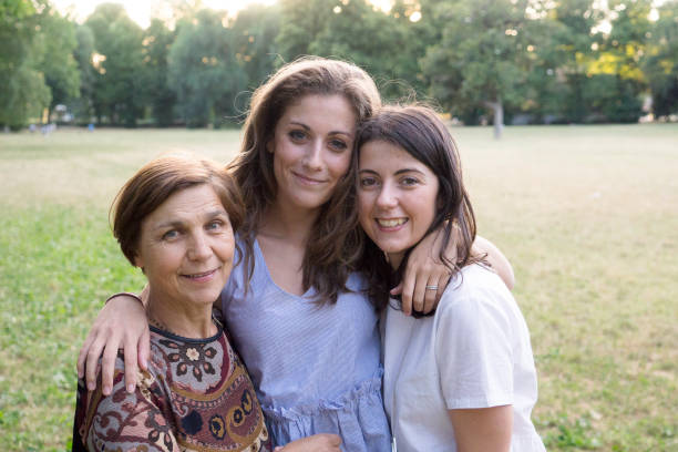 istock Mother and daughters embracing in a park 811273610
