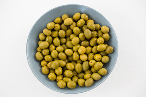 Close-up of marinated olives in bowl against white background