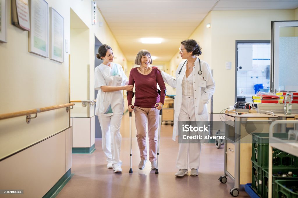 Ältere Frau mit Gehstock von Arzt und Krankenschwester geholfen - Lizenzfrei Krankenhaus Stock-Foto