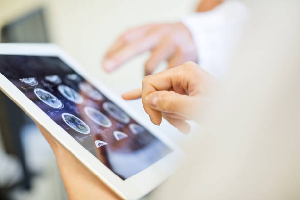 Medical team analyzing MRI scans on digital tablet Close up of doctors hands pointing at brain xrays images on digital tablet. Medical team in clinic analyzing MRI scans on digital tablet. body talk stock pictures, royalty-free photos & images