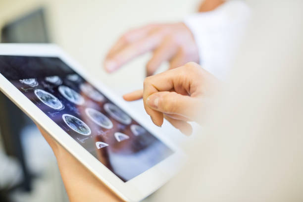 медицинская команда анализирует мрт на цифровом планшете - томография стоковые фото и изображения