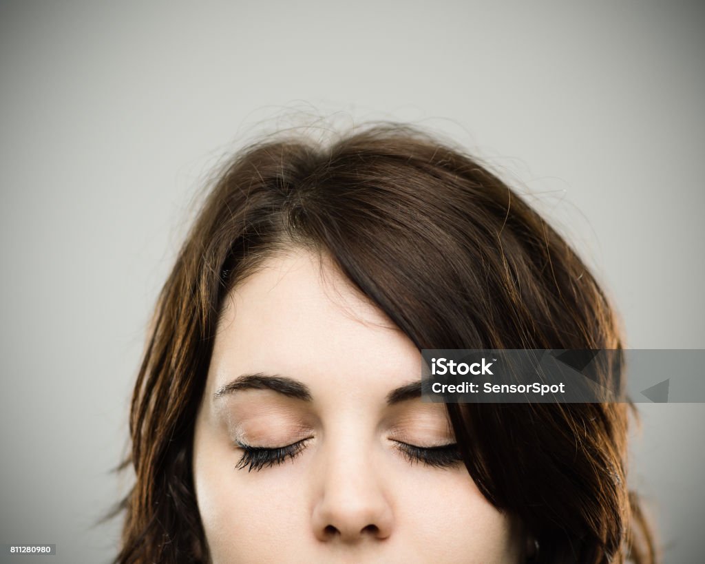 Close up of relaxed young woman Close up portrait of relaxed young caucasian woman against gray background. Horizontal shot of real woman with eyes closed Studio photography from a DSLR camera. Sharp focus on eyes. Women Stock Photo