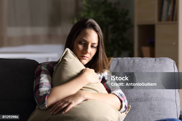 Sad Girl Embracing A Pillow At Home Stock Photo - Download Image Now - Depression - Sadness, Women, Sadness