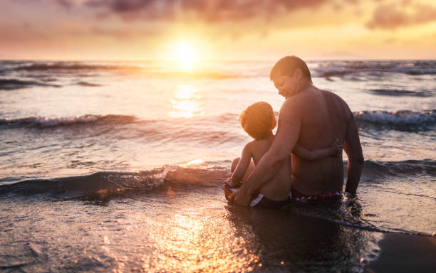 istock Happy father and son enjoying sea at sunset 811303710