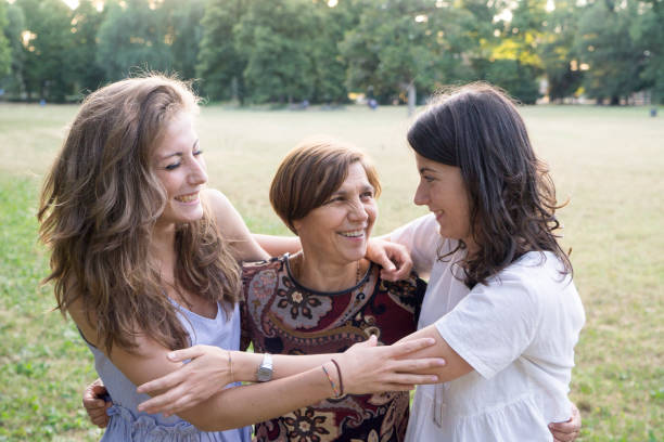 istock Mother and daughters embracing in a park 811310122