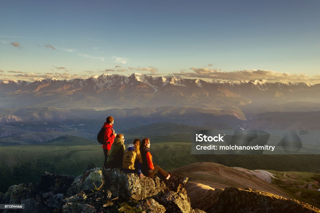 Friends on mountain top looking to sunset Four friends on mountain top looking to sunset Group Of People Stock Photo