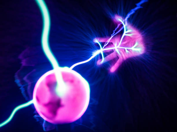 Electric flow: Hand on a plasma ball The science of electrical conduction as a boy's hand is placed on the glass of a plasma ball. plasma ball photos stock pictures, royalty-free photos & images