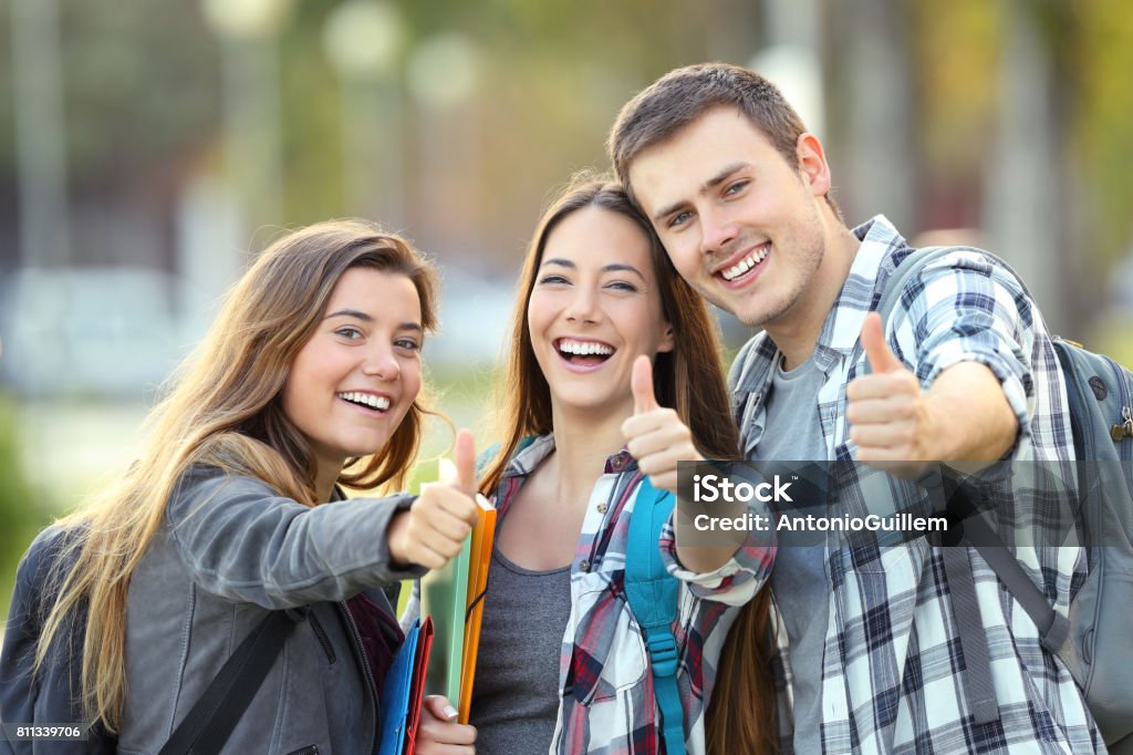 Tres estudiantes felices con los pulgares para arriba - Foto de stock de Estudiante libre de derechos