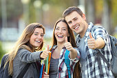 Three happy students with thumbs up