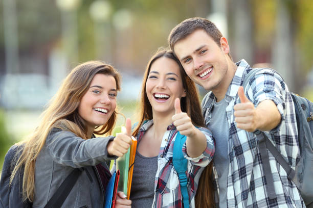 Three happy students with thumbs up Three happy students looking at you with thumbs up in an university campus teenager adolescence campus group of people stock pictures, royalty-free photos & images