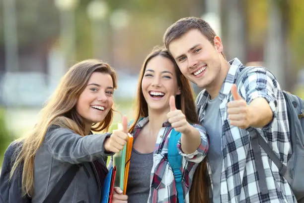Photo of Three happy students with thumbs up