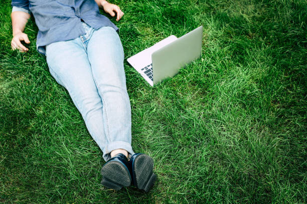 istock Low section of young man using laptop while resting on green grass 811353068