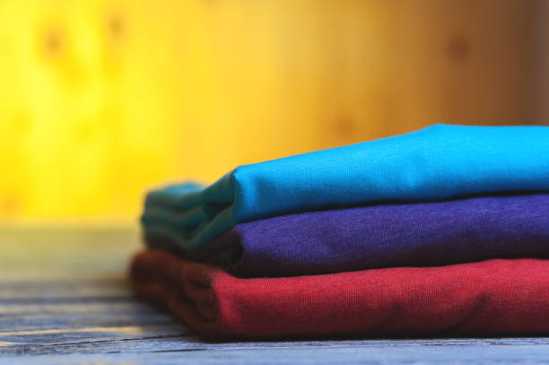 istock Stack of different cotton t-shirts on wooden table 811360378