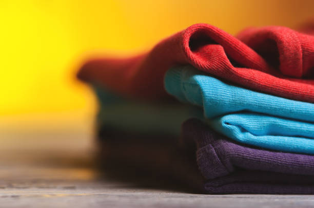 istock Stack of different cotton t-shirts on wooden table 811360492
