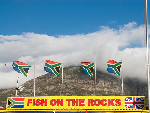 Hout Bay, South Africa - December 30, 2014: Iconic Fish on the Rocks with South African flags blowing in wind