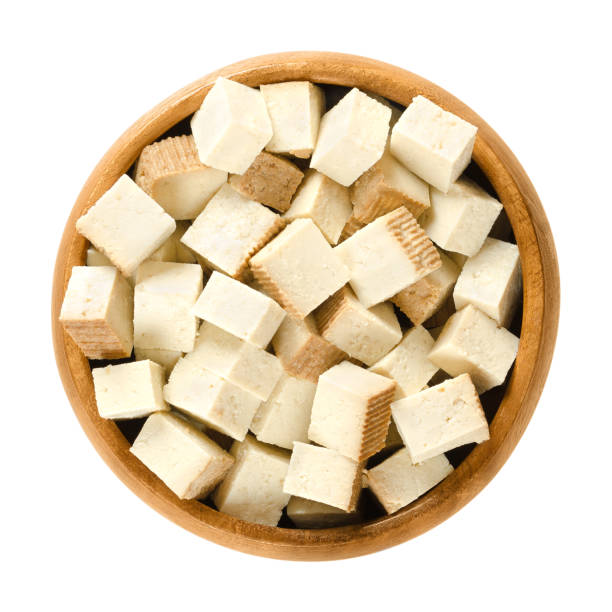 Smoked tofu cubes in wooden bowl Smoked tofu cubes in wooden bowl. Bean curd. Coagulated soy milk, pressed into firm white blocks. Component of Asian cuisine. Meat substitute. Isolated macro food photo close up from above over white tofu photos stock pictures, royalty-free photos & images