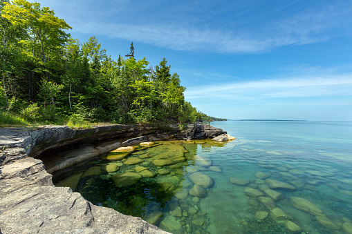 The clear waters of Lake Superior reveal large rocks and stones underwater. This cove, with pristine waters, is located near Au Train Michigan. Near Pictured Rocks National Lakeshore in the Upper Peninsula of Michigan.