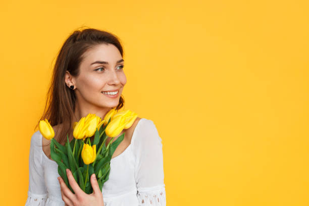 istock Young woman with yellow tulips posing 811393666