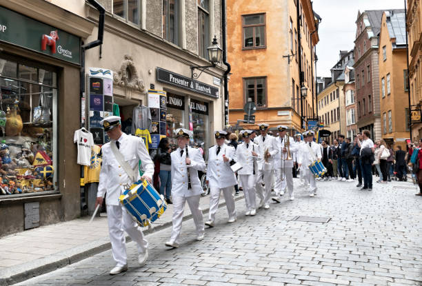military band  of the royal swedish navy marching through a street of gamla stan,the old town of stockholm - tourist photographing armed forces military imagens e fotografias de stock