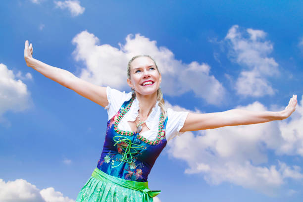 blonde woman in dirndl spreading her arms and smiles