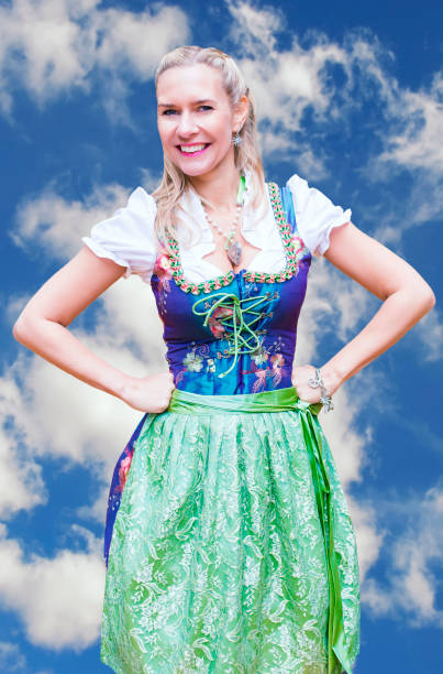 smiling blonde woman in dirndl in front of blue sky happy blonde woman in dirndl in front of blue sky dirndl traditional clothing austria traditional culture stock pictures, royalty-free photos & images