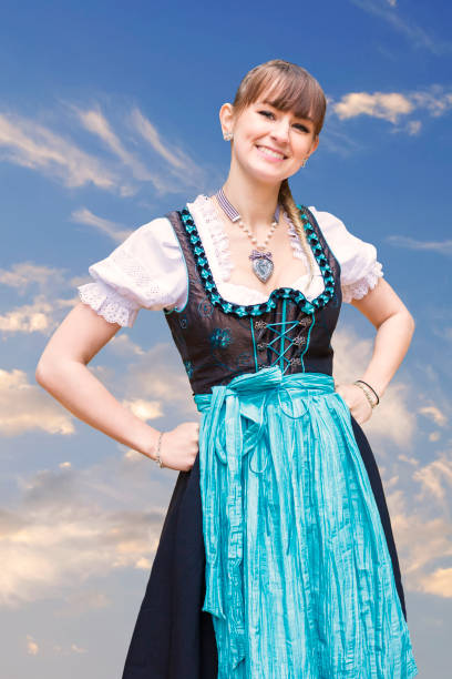 portrait of a young woman in dirndl a young woman in dirndl with blue sky in the background dirndl traditional clothing austria traditional culture stock pictures, royalty-free photos & images