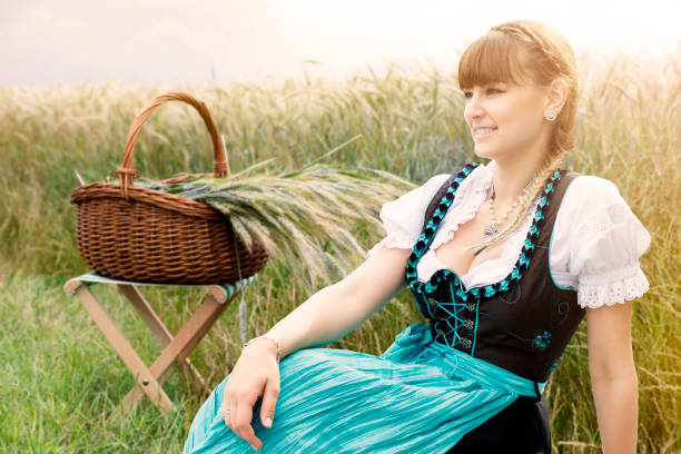 A beautiful young woman in a summer dress with a floral pattern next to a wooden well in a village. Shooting on a sunny summer day in the countryside